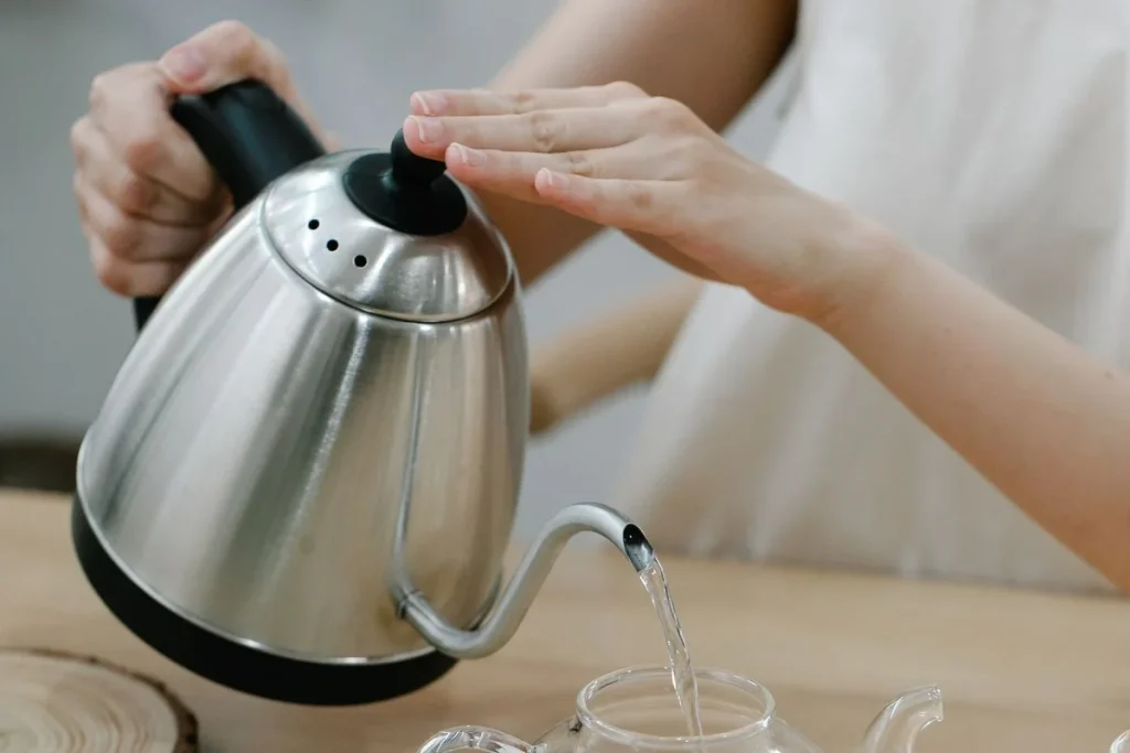 Bouilloire versant de l’eau dans une théière pour comparer les deux préparations